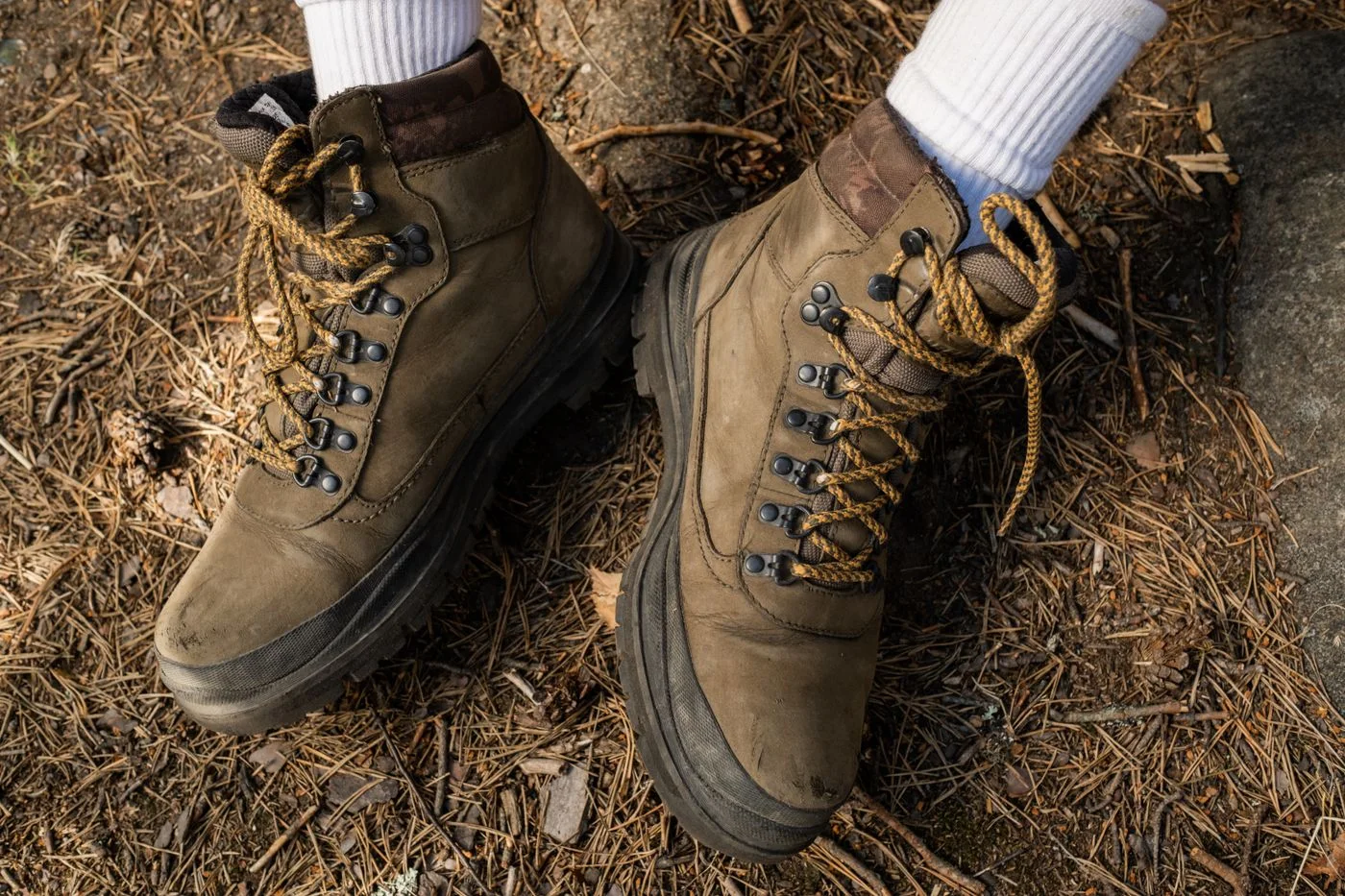 Hiking boots worn with socks on a forest path.