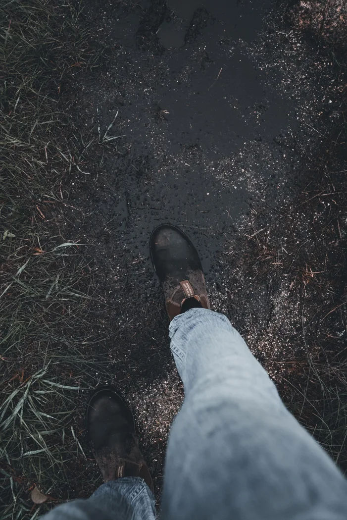 A hiking boot on a damp earth path.
