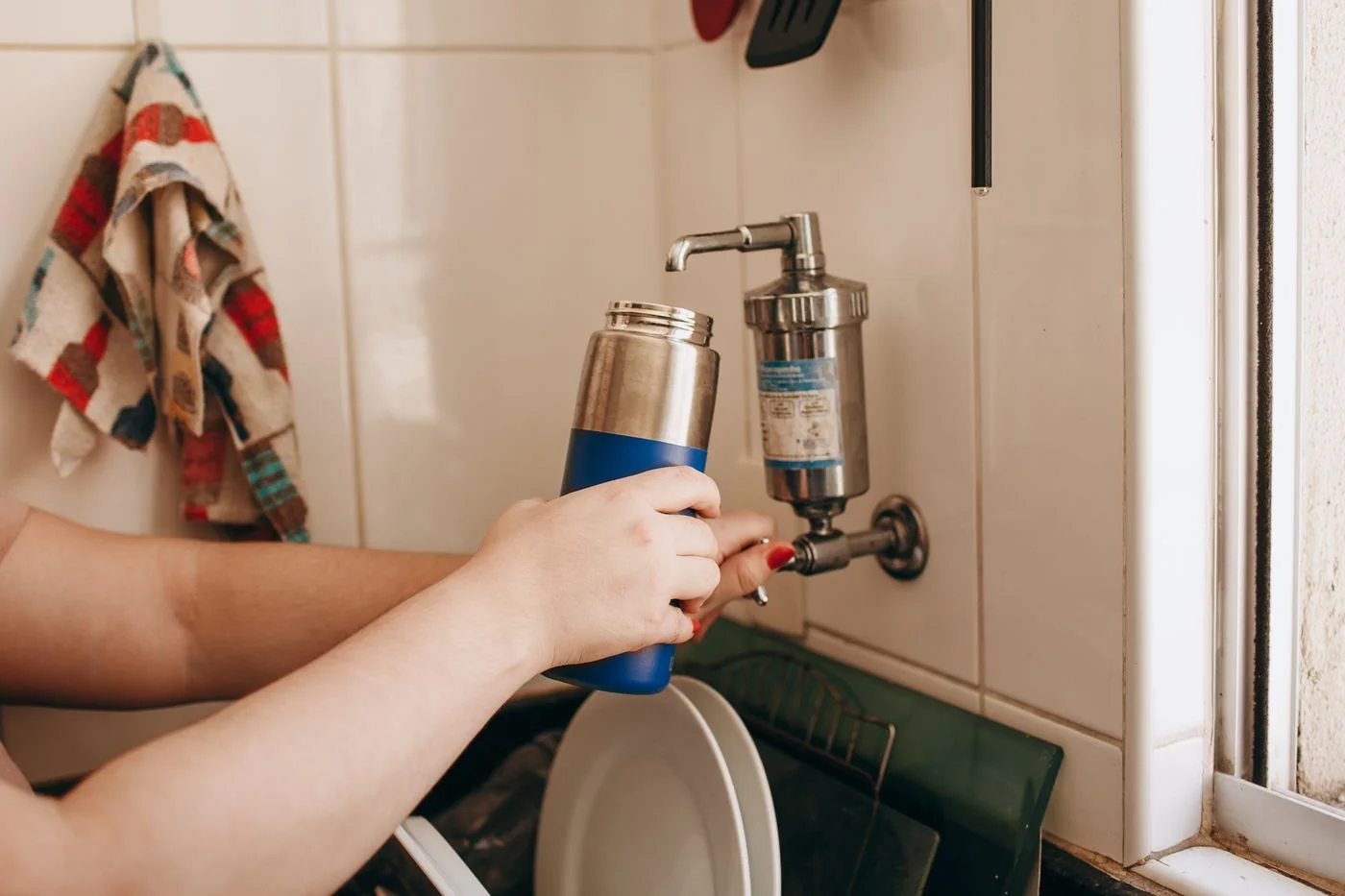 A water bottle being rinsed at a tap.