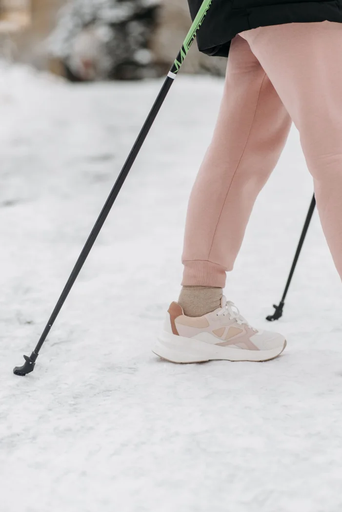 Trekking poles in use on winter ground.